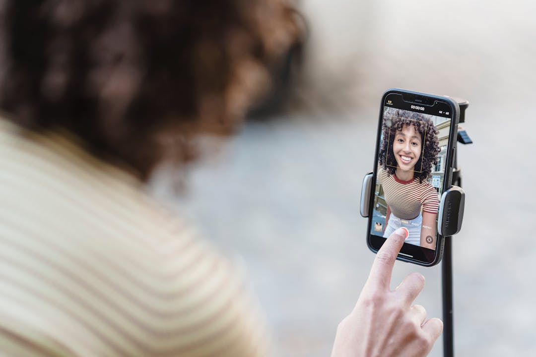 Person som ler för en selfie som tas med en smartphone på ett stativ.